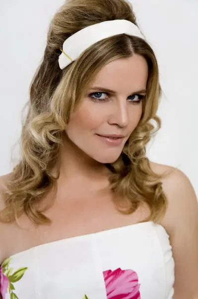 Portret Leonore Surian, glumice, u bijeloj haljini s cvjetnim uzorkom i bijelom trakom u kosi.