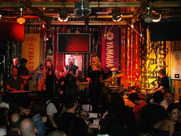 Leonora Surian nastupa u PB Clubu s bendom, okružena publikom.