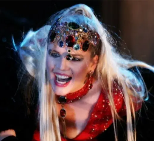 Žena s krunom i crvenim nakitom na sceni