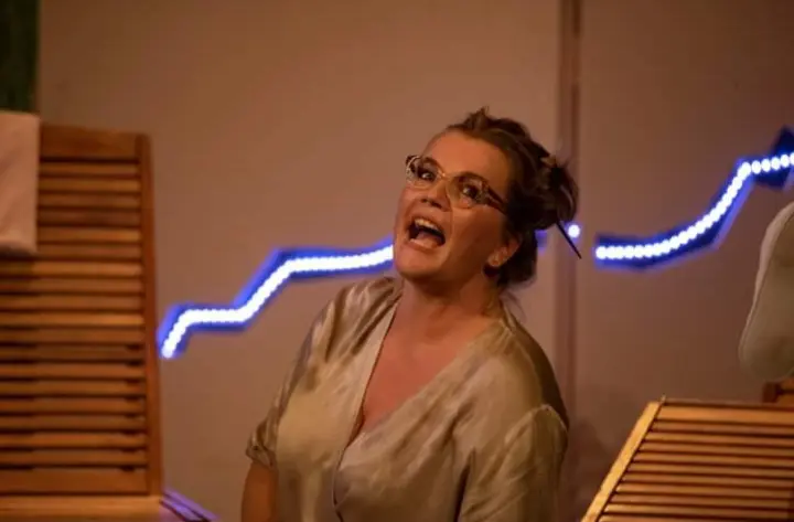 Leonora Surian u sceni iz predstave, nosi naočale i izgleda radosno